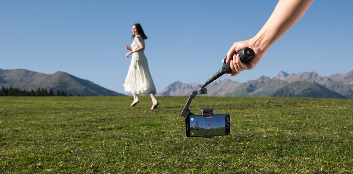 Kobieta na łące nagrywana z niskiego ujęcia telefonem na gimbalu DJI Osmo Mobile 8